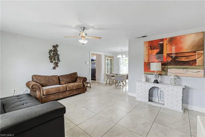 Tiled living room featuring a fireplace and ceiling fan with notable chandelier