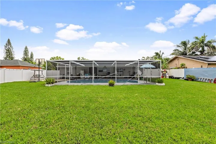 Back of house with a yard, a fenced in pool, and a lanai