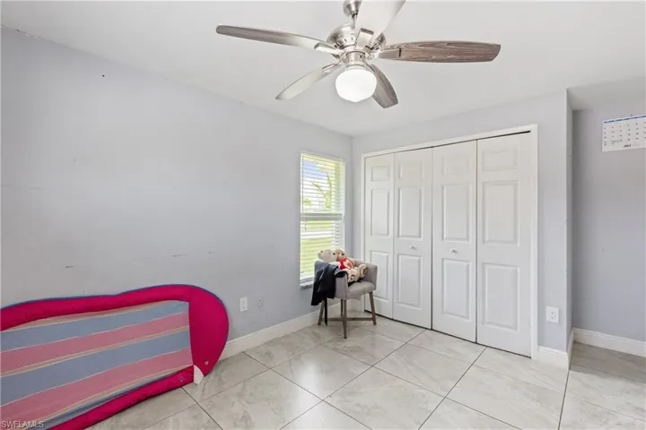 Tiled bedroom featuring ceiling fan and a closet