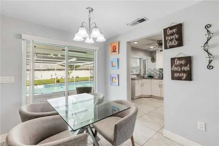 Tiled dining area with ceiling fan with notable chandelier