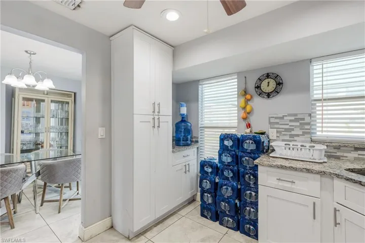 Kitchen featuring ceiling fan with notable chandelier, backsplash, a wealth of natural light, and light tile patterned floors