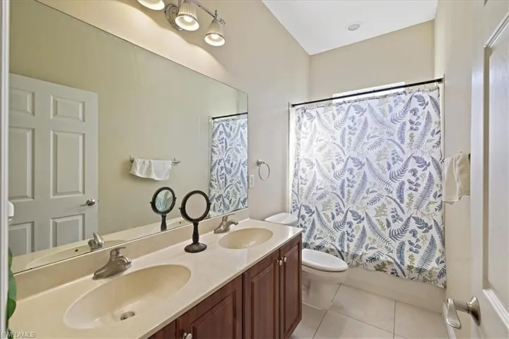 Bathroom featuring double vanity, light tile patterned flooring, and shower / bath combination with curtain