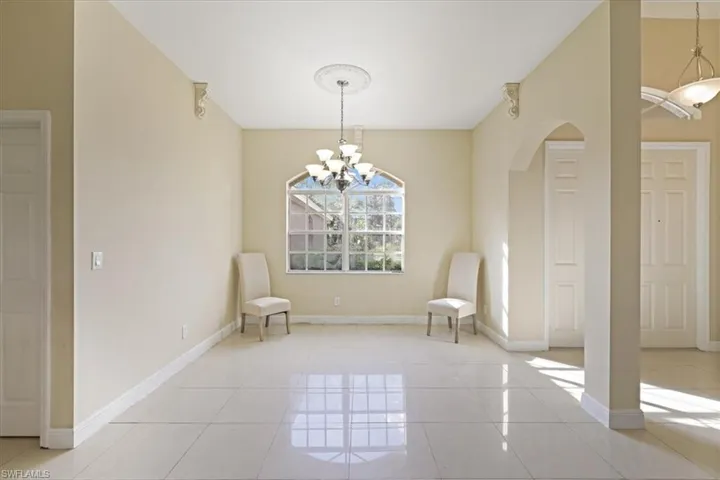 Unfurnished room featuring a chandelier, light tile patterned floors, and arched walkways