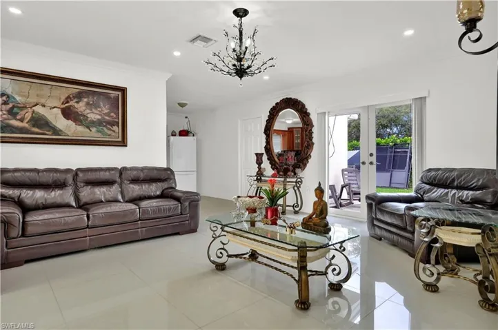 Living room featuring ornamental molding, an inviting chandelier, french doors, and light tile patterned floors