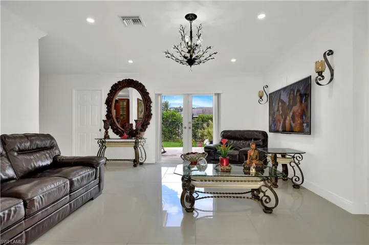 Living room featuring french doors, ornamental molding, and an inviting chandelier