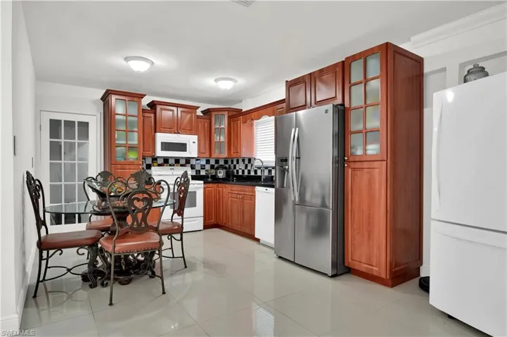 Kitchen with white appliances, sink, light tile patterned floors, and backsplash