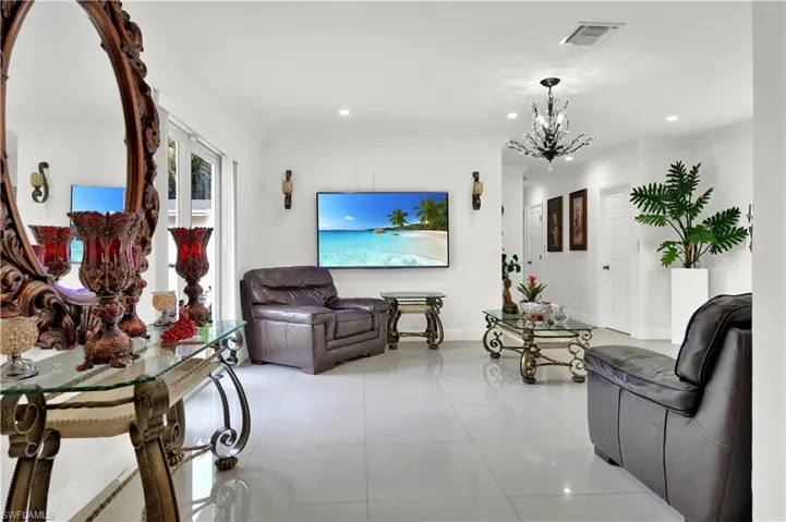 Tiled living room with ornamental molding and a notable chandelier
