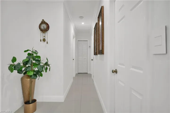 Hall with light tile patterned flooring and ornamental molding