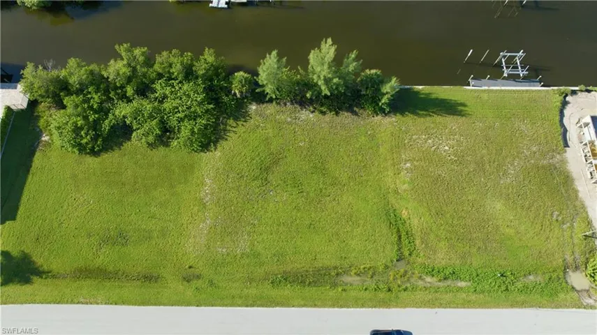 Cleared lot featuring direct water frontage, a concrete seawall, and mature tropical landscaping