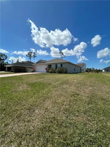 View of front of property with a garage, concrete driveway, and a front lawn