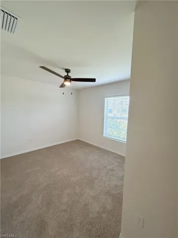 Empty room with visible vents, baseboards, ceiling fan, and carpet flooring