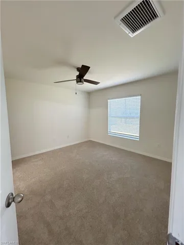 Unfurnished room featuring visible vents, baseboards, carpet, and a ceiling fan