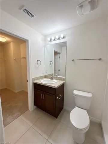 Bathroom featuring tile patterned floors, visible vents, toilet, and vanity