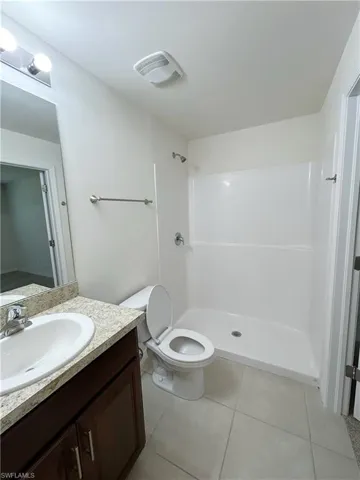 Full bathroom with visible vents, toilet, tile patterned floors, vanity, and a shower