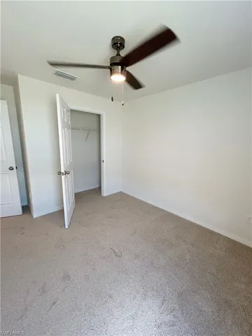 Unfurnished bedroom with baseboards, visible vents, carpet floors, ceiling fan, and a closet