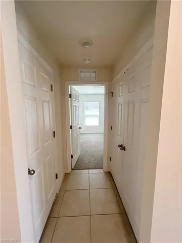 Corridor with visible vents, light colored carpet, and light tile patterned flooring