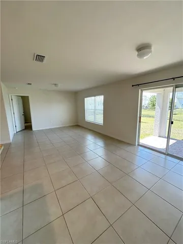 Unfurnished room with light tile patterned floors, visible vents, and baseboards