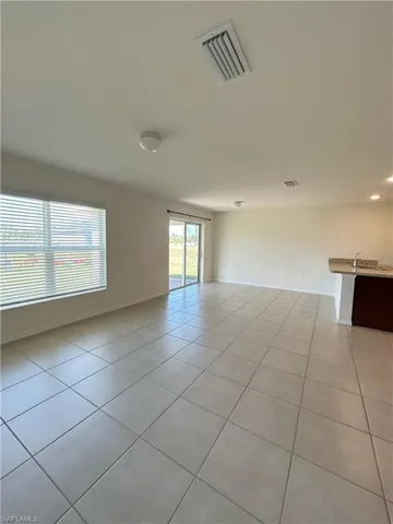 Unfurnished room with light tile patterned floors, visible vents, and baseboards