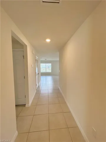 Hall featuring light tile patterned floors and baseboards