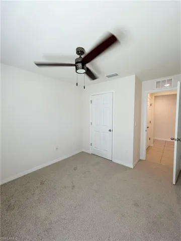 Unfurnished bedroom featuring light carpet, visible vents, a ceiling fan, and baseboards
