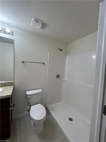 Full bathroom featuring tile patterned flooring, baseboards, toilet, vanity, and a shower