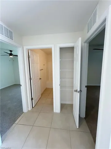 Hall with visible vents, light colored carpet, and light tile patterned flooring