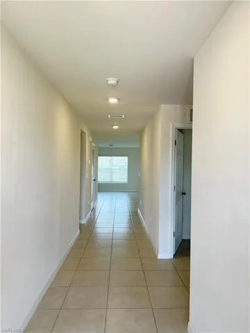 Hallway featuring light tile patterned flooring and baseboards