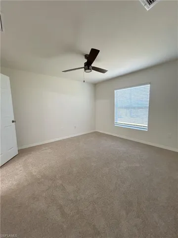 Carpeted spare room with visible vents, baseboards, and ceiling fan