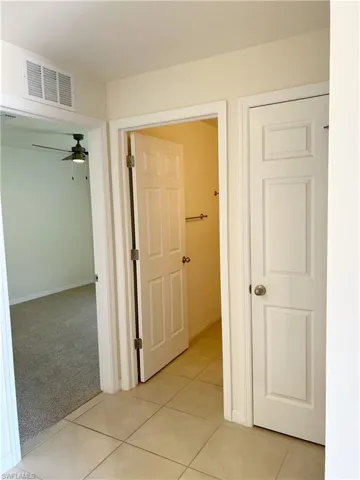Hall featuring light tile patterned flooring, visible vents, and light colored carpet