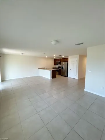 Unfurnished living room with light tile patterned flooring, baseboards, visible vents, and a sink