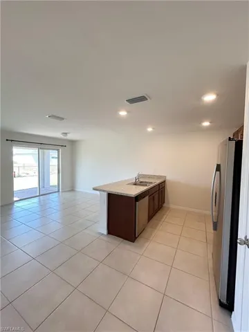 Kitchen featuring visible vents, a sink, open floor plan, appliances with stainless steel finishes, and light tile patterned floors