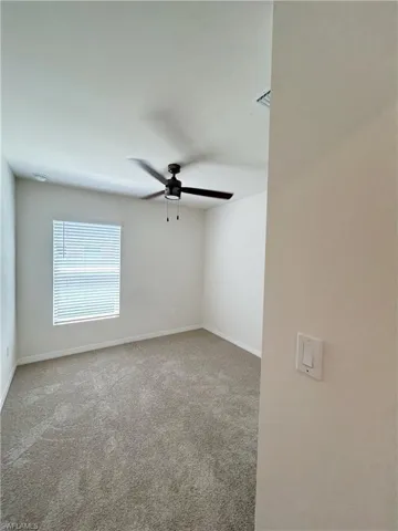 Carpeted spare room with baseboards and a ceiling fan
