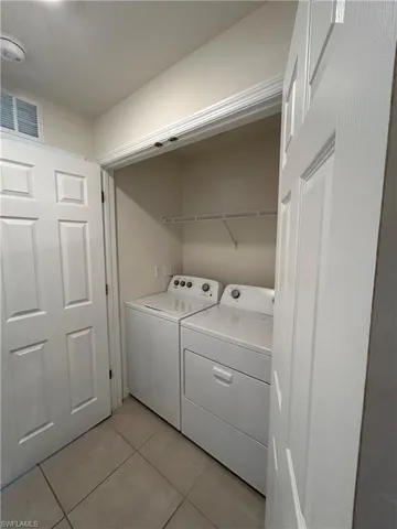 Laundry room featuring light tile patterned floors, laundry area, washer and dryer, and visible vents