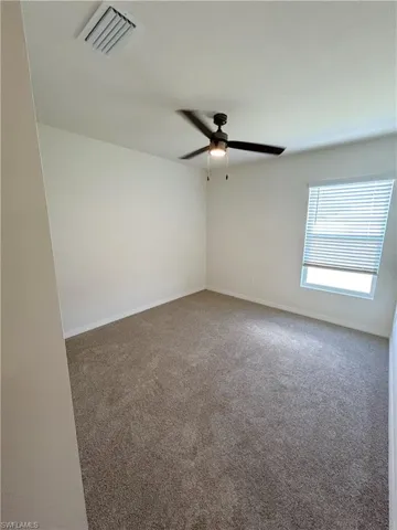 Carpeted empty room featuring visible vents, baseboards, and ceiling fan