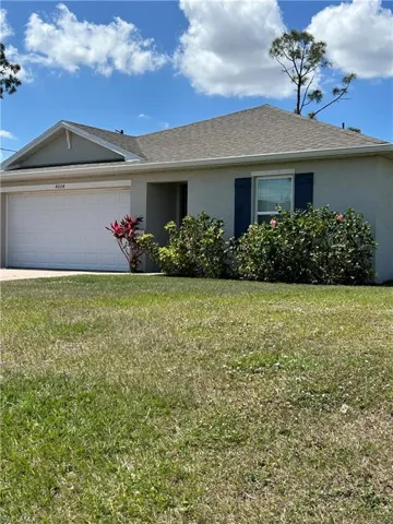 Ranch-style house with stucco siding, an attached garage, a front lawn, and roof with shingles