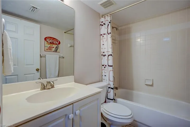 Bathroom with shower / bath combination with curtain, visible vents, vanity, and toilet