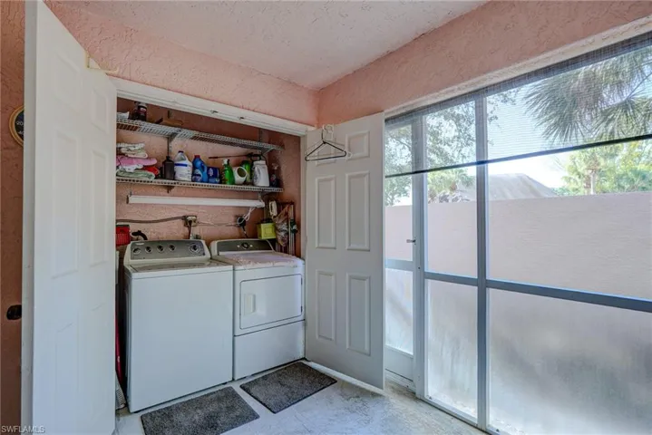 Laundry area with washing machine and clothes dryer, a textured wall, and laundry area