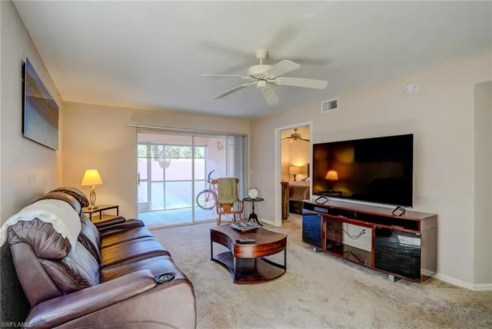 Carpeted living area featuring visible vents, a ceiling fan, and baseboards