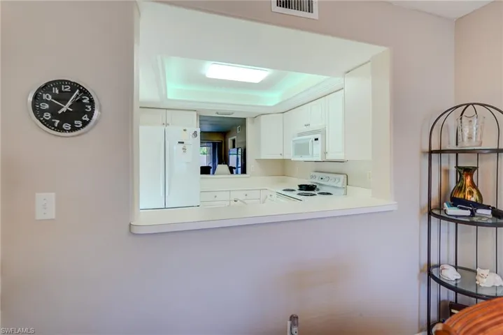 Room details with light countertops, visible vents, white appliances, a peninsula, and white cabinetry