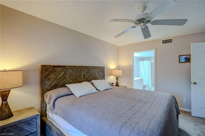 Bedroom with visible vents, a ceiling fan, carpet floors, ensuite bath, and baseboards