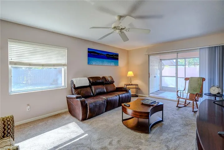 Carpeted living area with baseboards and a ceiling fan