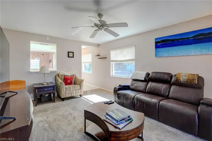 Living room with ceiling fan, baseboards, and carpet