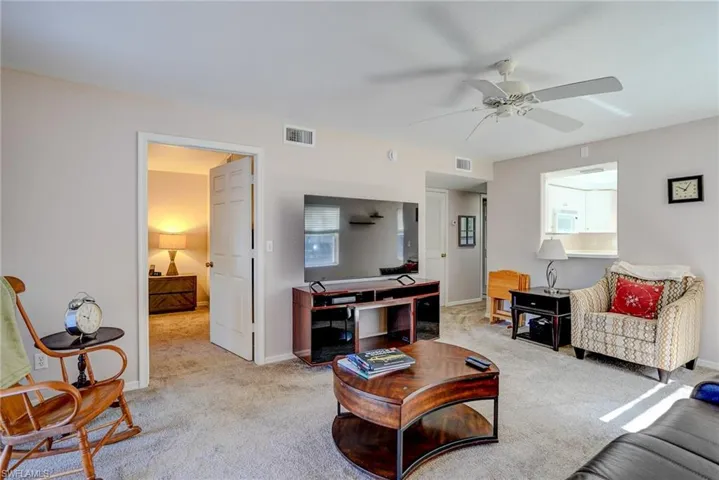 Living area featuring ceiling fan, light carpet, visible vents, and baseboards