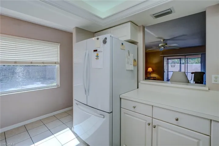Kitchen featuring white cabinets, light countertops, visible vents, a ceiling fan, and freestanding refrigerator