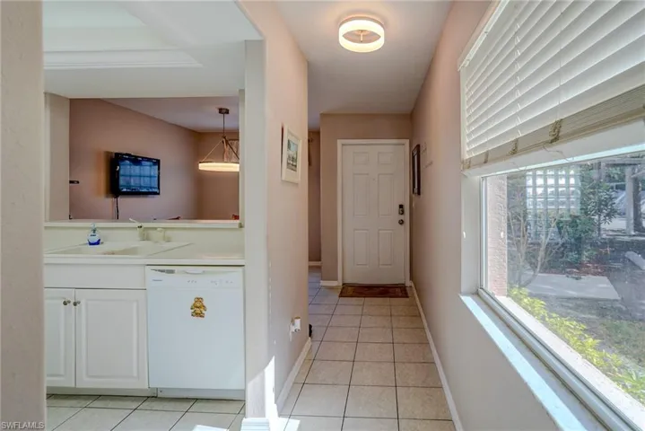 Doorway with baseboards, light tile patterned floors, and a sink