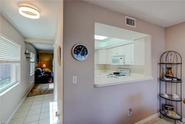 Hall with baseboards, visible vents, and light tile patterned floors