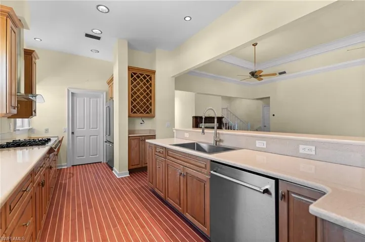Kitchen featuring wood-finish flooring, recessed lighting, wood cabinetry, a built-in wine rack, and a stainless steel double basin sink