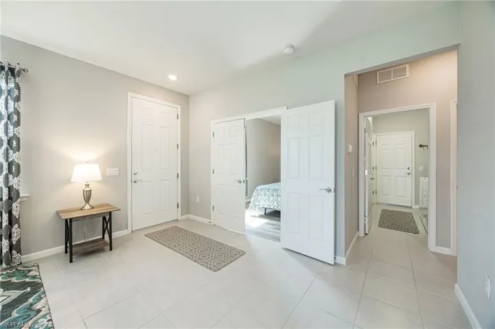 Kitchen featuring white cabinetry, a kitchen breakfast bar, stainless steel fridge with ice dispenser, decorative backsplash, and light stone countertops