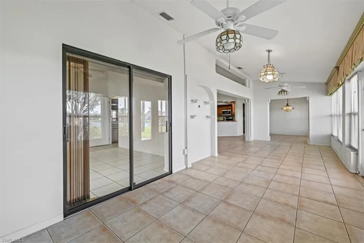 Spare room featuring light tile patterned floors, vaulted ceiling, and ceiling fan