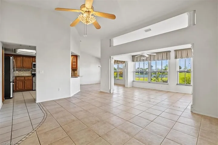 Unfurnished living room featuring high vaulted ceiling, light tile patterned floors, and ceiling fan